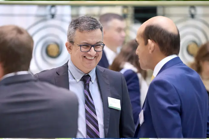 Man in a suit smiling during a corporate networking event